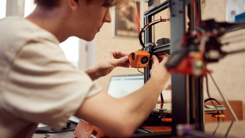 Mann arbeitet am 3D-Drucker, um ihn aufzuheizen