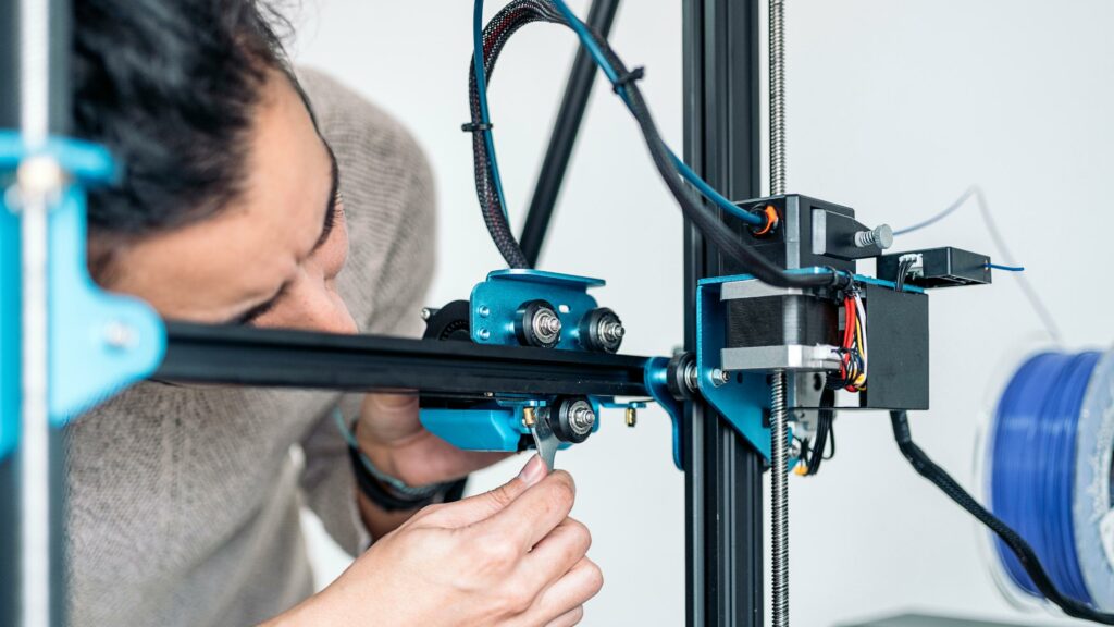 Männliche Person, die einen 3D-Drucker repariert, der ein schleifendes Geräusch macht