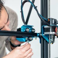 Männliche Person, die einen 3D-Drucker repariert, der ein schleifendes Geräusch macht