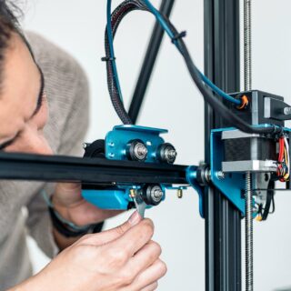 mannelijke persoon repareert 3d printer die een knarsend geluid maakt