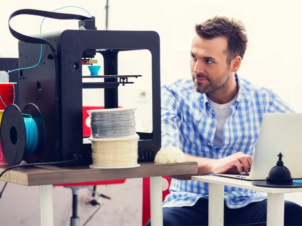 man sitting next to 3d printer