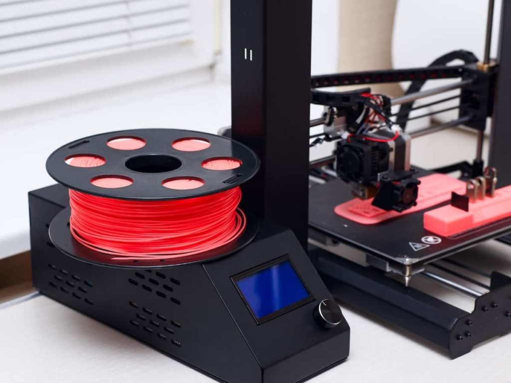 3d printer printing an object with red filament