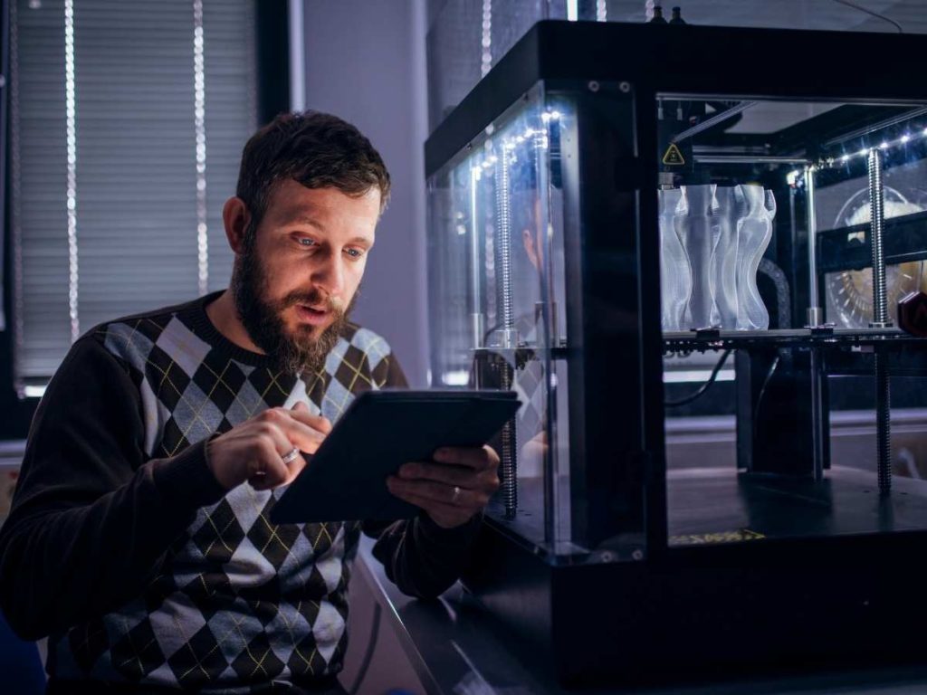 engineer sitting next to a 3d printer