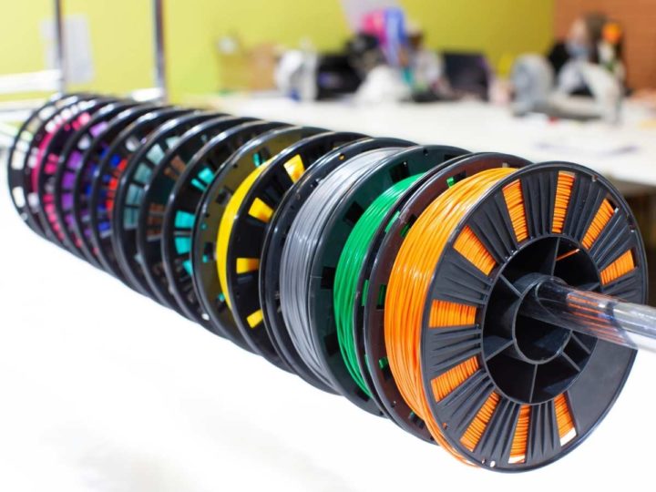 multiple spools of filament in different colors hanging on a metal bar