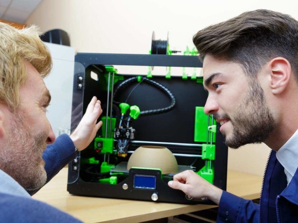 2 man looking at a 3d printer