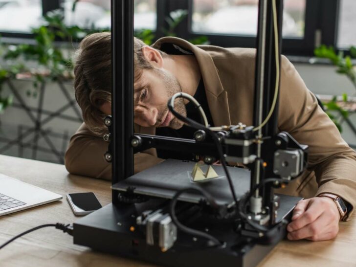 men looking at his 3d printer printing an object