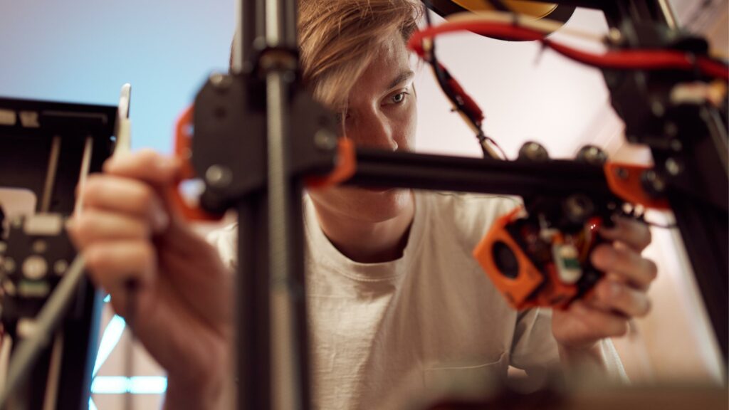 male person doing maintanenance on a 3d printer