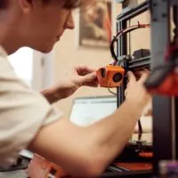 man working on 3d printer to heat it up