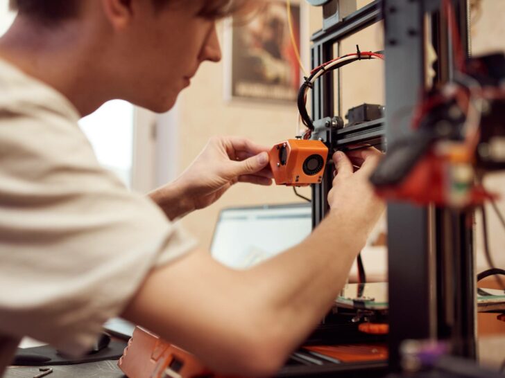 man working on 3d printer to heat it up