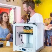 man and woman standing behind a 3d printer and filament