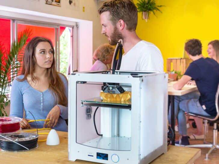 man and woman standing behind a 3d printer and filament